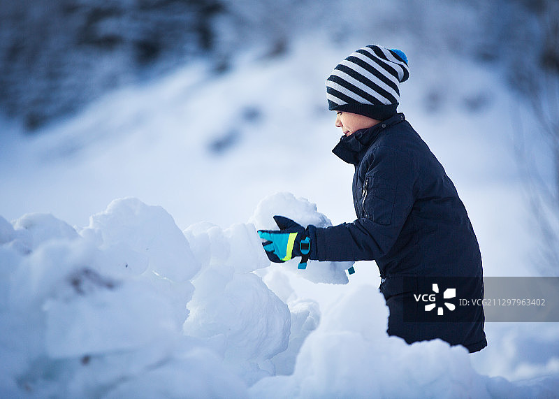 挪威桑德福德，一个男孩抱着雪站在田野上图片素材