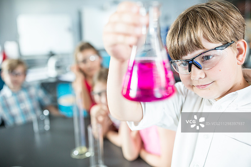 戴着安全眼镜的孩子在课堂上拿着烧杯通过实验学习科学图片素材