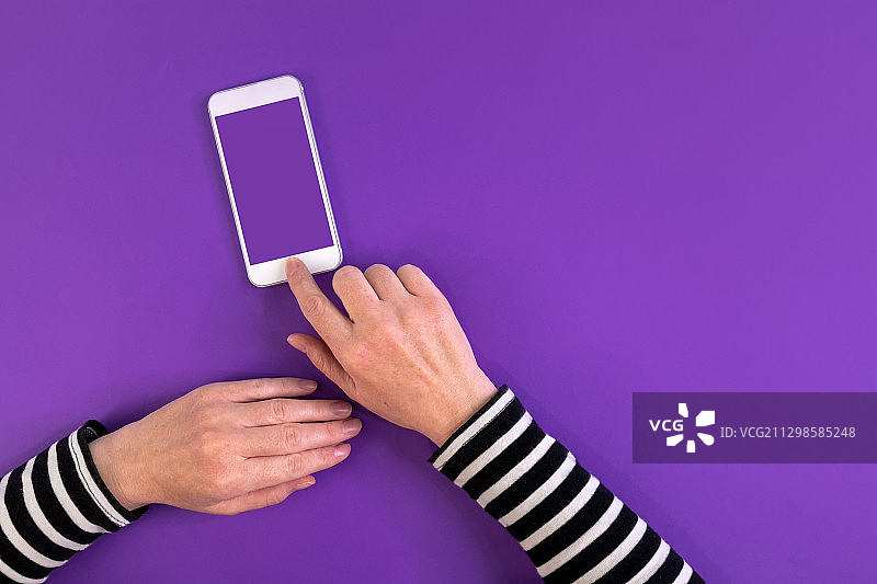 用手机在紫色背景下裁剪手，诺维萨德，塞尔维亚图片素材