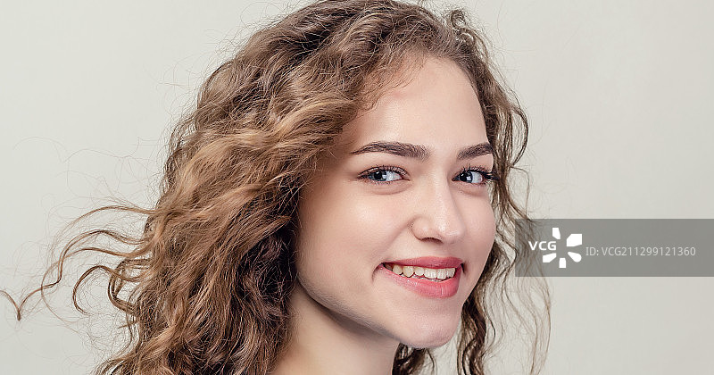 微笑的年轻女人的特写肖像与白色的背景卷头发图片素材