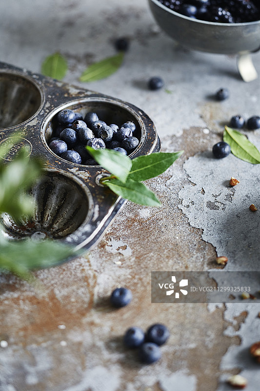蓝莓和月桂叶装在松饼盘上，放在乡村的表面上图片素材