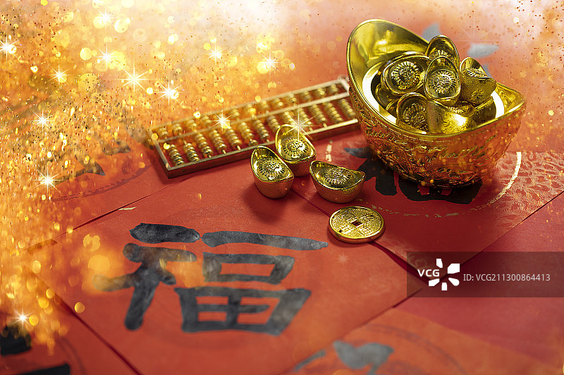 福字春联上放着金光闪闪的金元宝金币和算盘图片素材