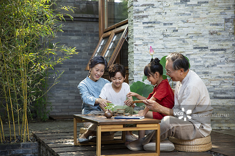 爷爷、奶奶教孙女、孙子两个孩子在庭院学习中国茶道图片素材