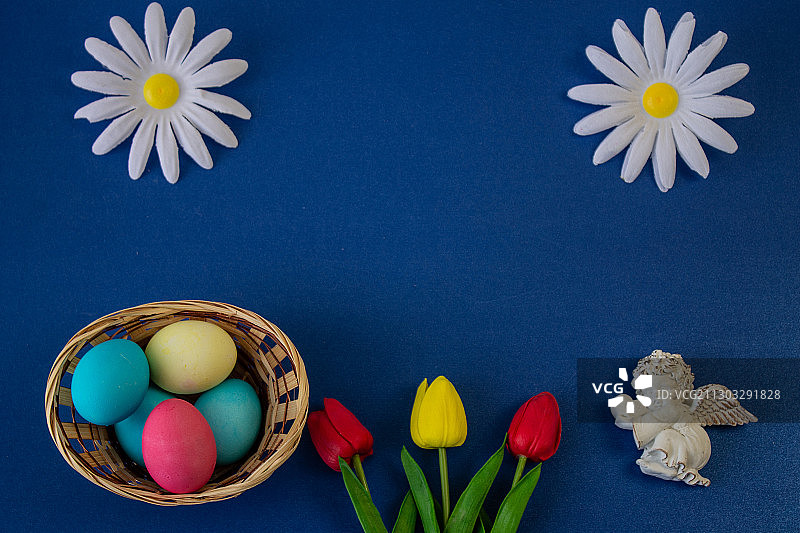 正上方拍摄的复活节彩蛋与花在蓝色的背景图片素材