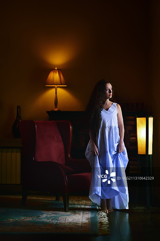 美丽的女人穿着现代的蓝色连衣裙在一个经典的内饰图片素材
