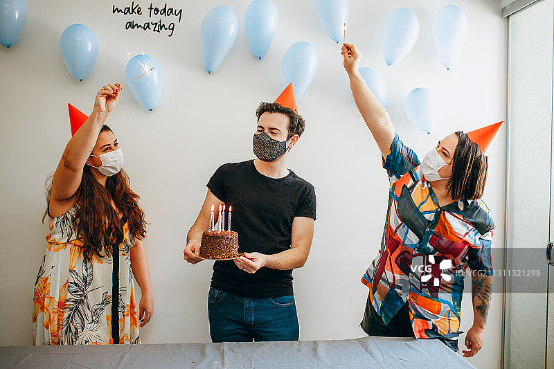 巴西米纳斯吉拉斯州贝洛奥里藏特，年轻的成年人朋友们戴着面具庆祝生日图片素材