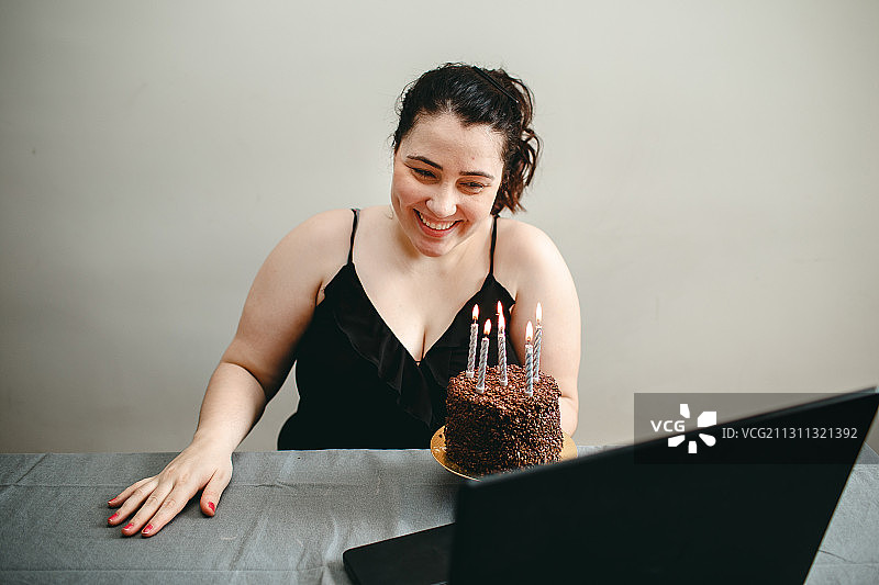 巴西米纳斯吉拉斯州贝洛奥里藏特，一名年轻的成年巴西妇女在网上用笔记本电脑摄像头庆祝她的生日图片素材