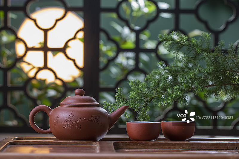 月光下窗花旁桌上的中国茶壶和茶杯图片素材