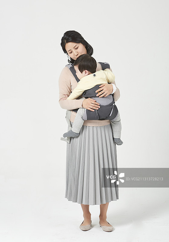 母亲站在白色的背景下拥抱着婴儿图片素材