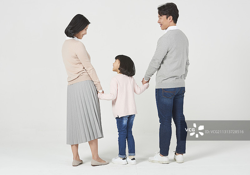 三名家庭成员手牵着手站在白色背景的后视图图片素材