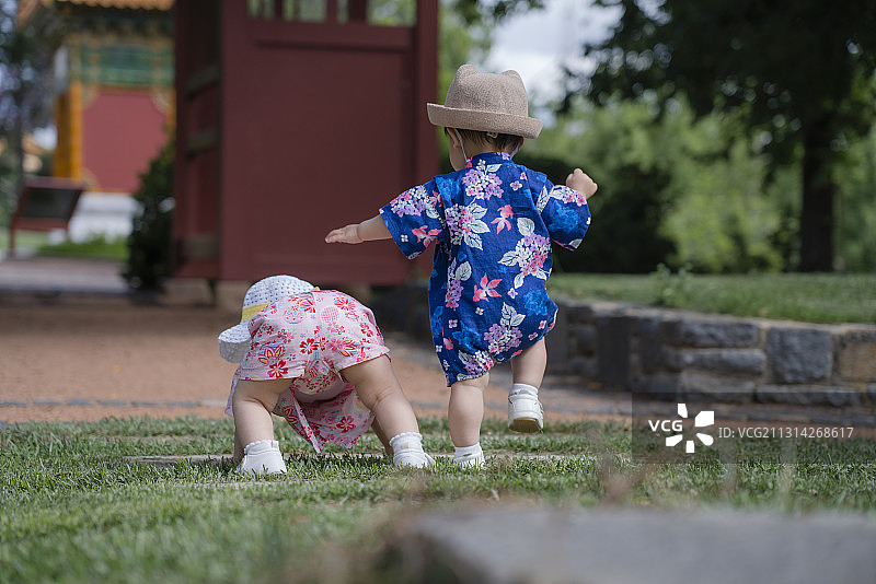 红亭子前石阶处的两个快乐的花样婴儿图片素材