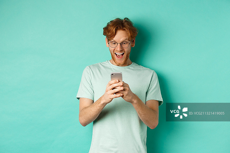 在绿松石背景下使用手机的微笑男子肖像图片素材