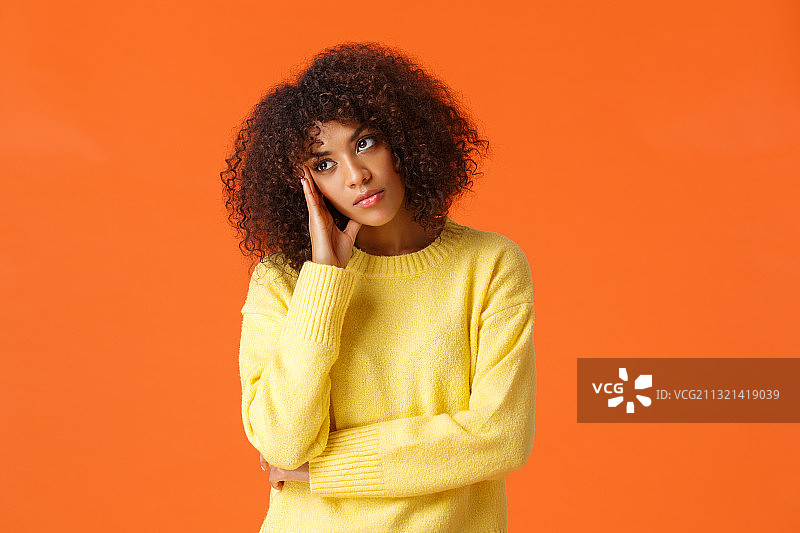 年轻女子的肖像与非洲发式站在橙色的背景图片素材