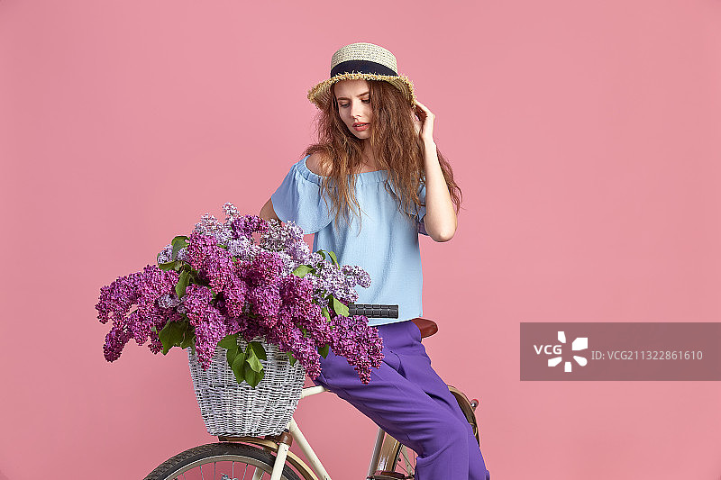 骑着自行车的女人靠着粉红色的花站着图片素材