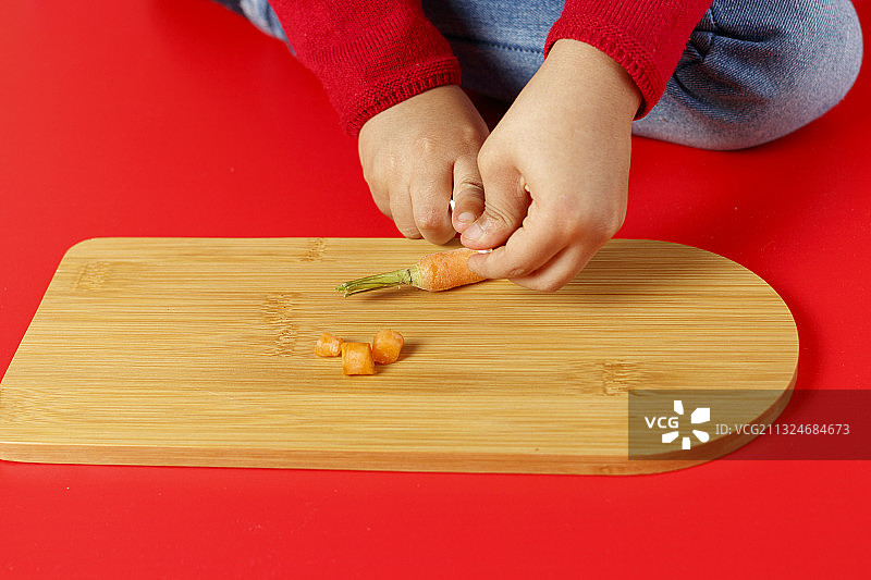 秘鲁利马，一名儿童正在桌上用手切小胡萝卜图片素材
