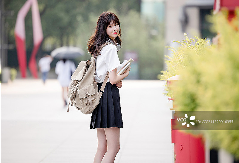 在户外，漂亮美丽的亚洲女大学生图片素材