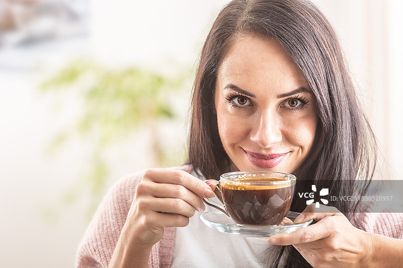 微笑的女人在家里喝咖啡的肖像图片素材