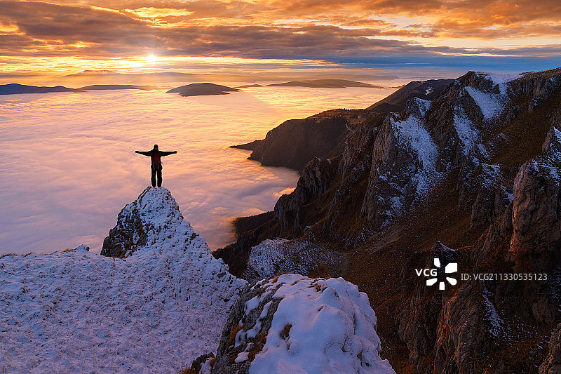 夕阳西下，一个人站在白雪皑皑的山上图片素材