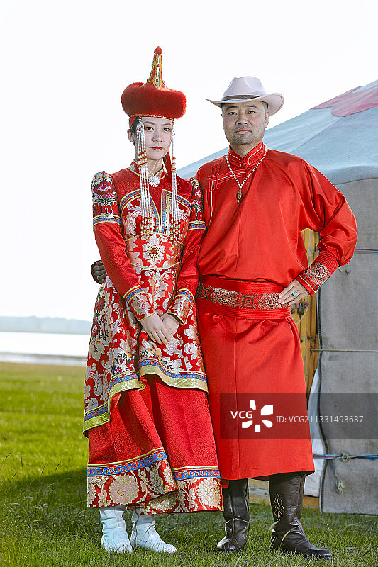 草原上蒙古包前穿蒙古族传统服饰的年轻夫妻图片素材