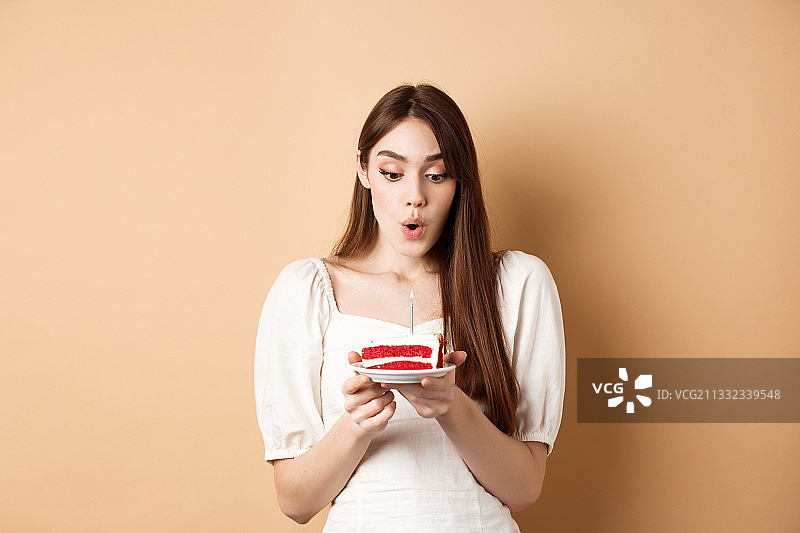 年轻女子吃蛋糕，而站在棕色的背景图片素材