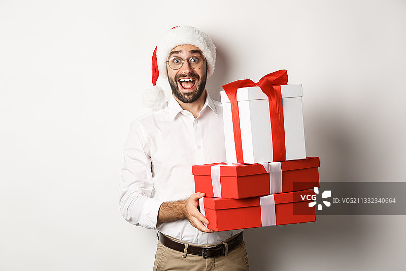 在白色背景下，一个微笑的男人拿着圣诞礼物的肖像图片素材