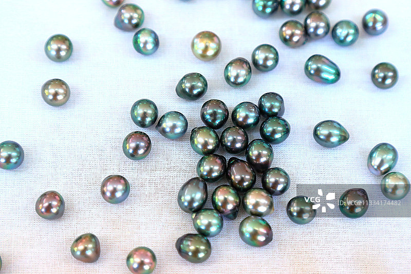 在零售销售。这种被称为“塔希提黑珍珠”的珠子是一种AOC，其珍珠色调从绿色到深或浅的颜色，在深浅的阴影中拉出紫色。图片素材