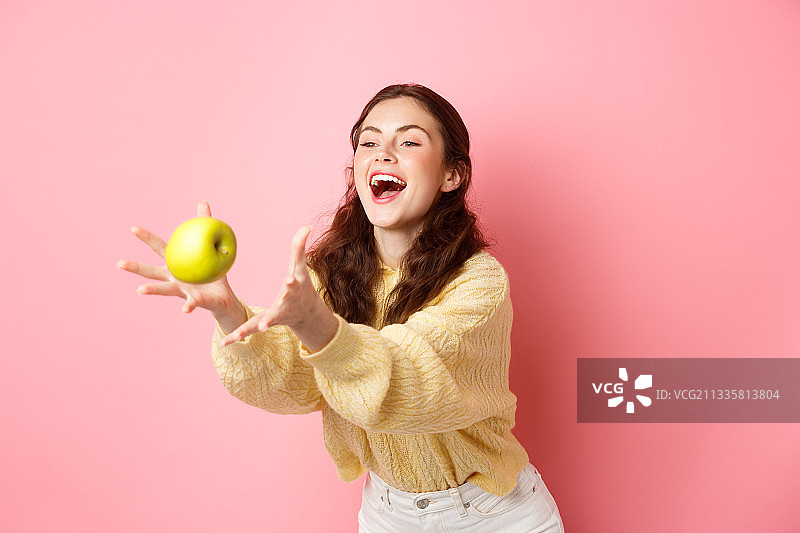 快乐可爱的女孩抓了一个苹果笑了，是时候吃健康午餐了图片素材