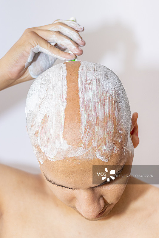 一名男子用白色泡沫剃光头图片素材