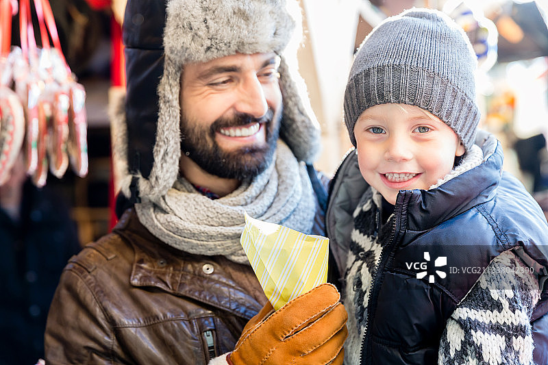 父亲和儿子在圣诞市场上吃甜烤杏仁图片素材