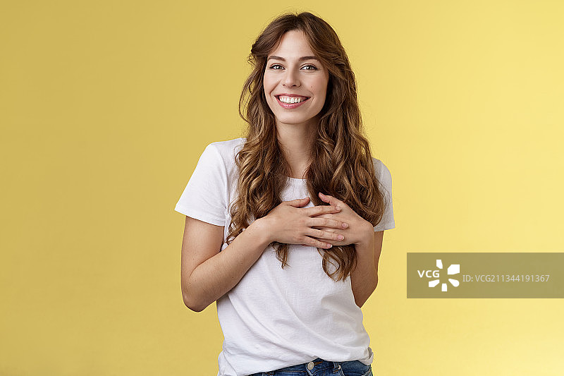 微笑的年轻女子肖像站在黄色的背景图片素材