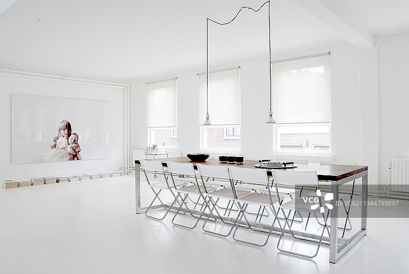 白色地板的极简主义餐厅的长桌子周围有折叠椅图片素材