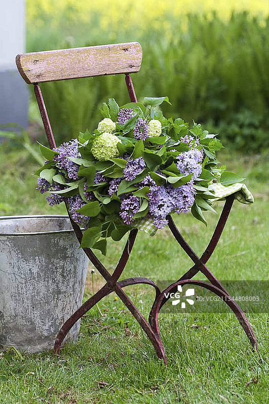 在花园的椅子上放着丁香和荚蒾的花束图片素材
