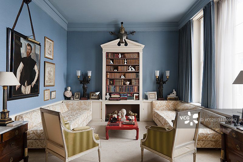 对称的，韦奇伍德蓝色客厅与书柜，沙发，红色漆咖啡桌和历史肖像图片素材