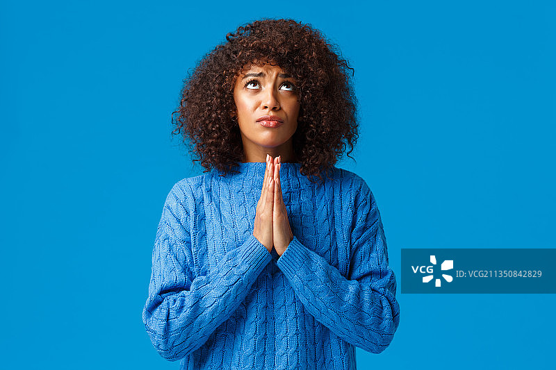 年轻女子站在蓝色背景下祈祷图片素材