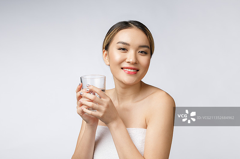 一名微笑的年轻女子手持水杯，背景为白色图片素材