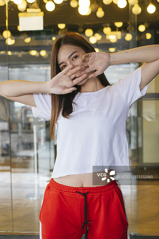 时尚肖像-美丽的亚洲年轻女子在白色衬衫和红色运动裤在美丽的黄色背景摆姿势。图片素材