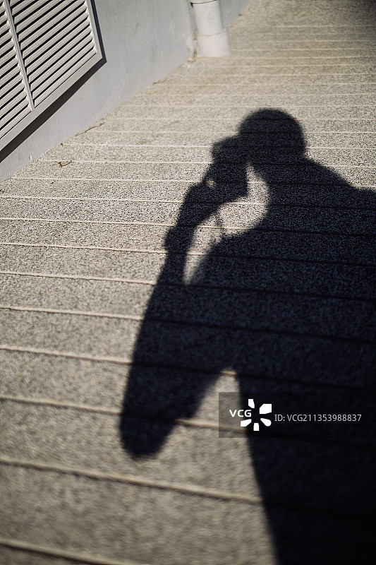阴影的摄影师家伙拿着相机的斜坡路径与线。图片素材