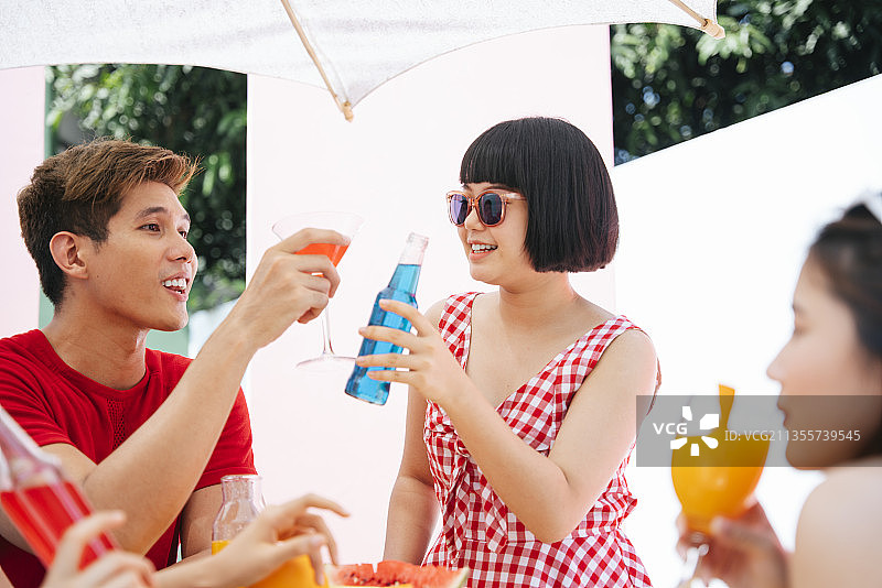 三个亚洲人在夏季户外聚会上享受饮料。图片素材