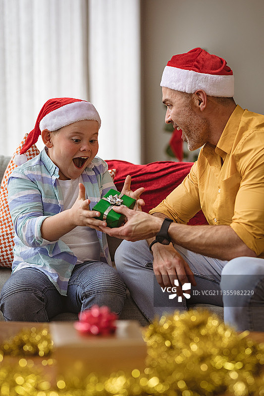 一位白人父亲在圣诞节期间给在家的儿子送圣诞礼物图片素材