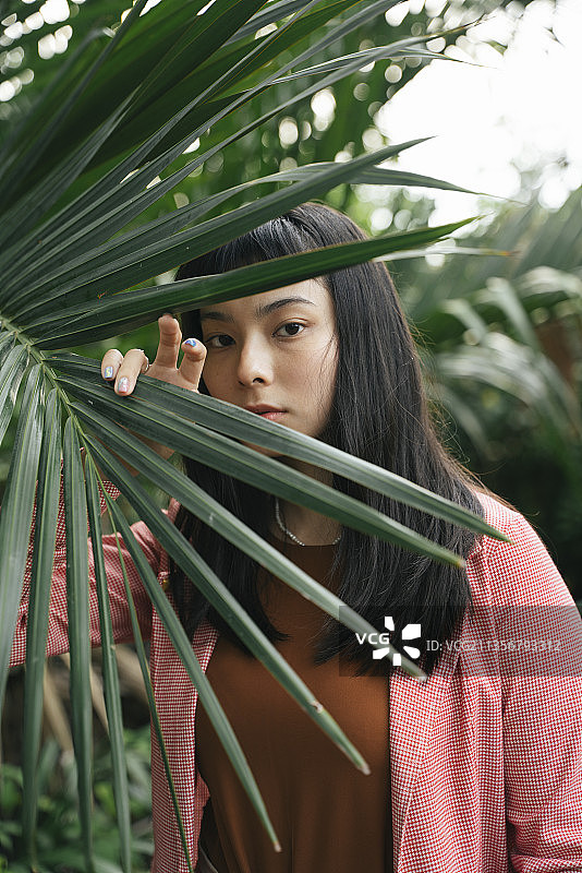 特写肖像-亚洲商业妇女在正式衬衫与树叶摆姿势。图片素材
