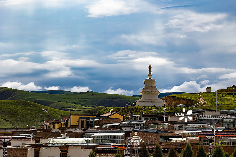 多云的天气，甘肃甘南合作市，米拉日巴佛阁旁寺庙建筑群中的白塔图片素材
