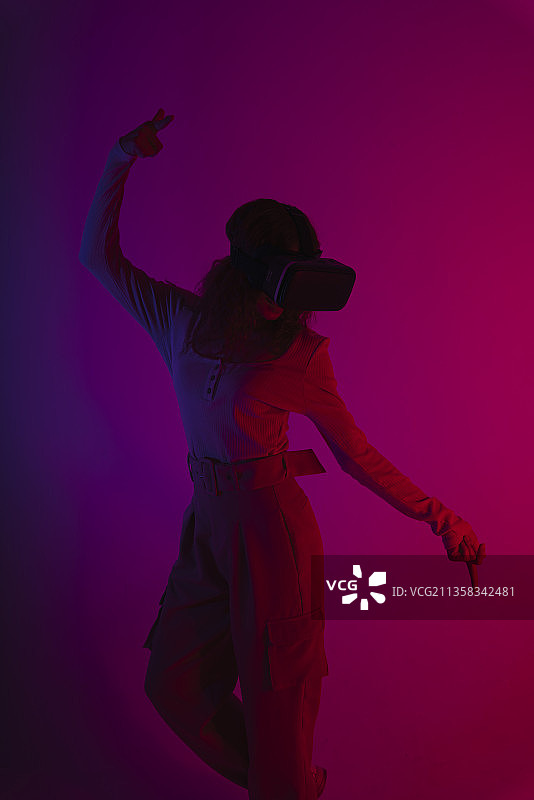 快乐女人在霓虹灯背景下戴着虚拟现实VR眼镜。图片素材