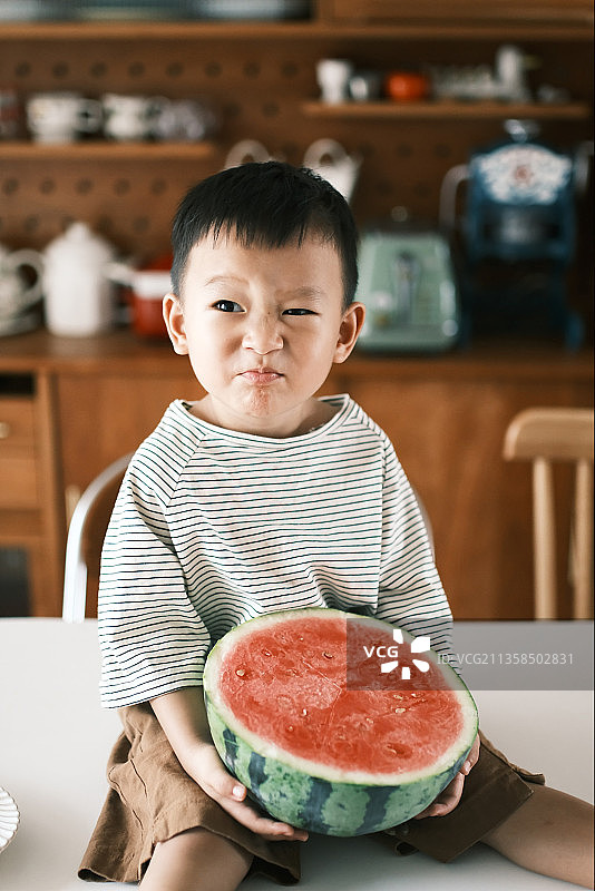 一个男孩在家里吃西瓜图片素材