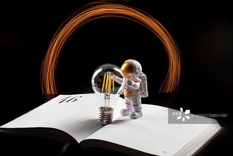 站在书本上手握灯泡的宇航员穿越时空之门图片素材