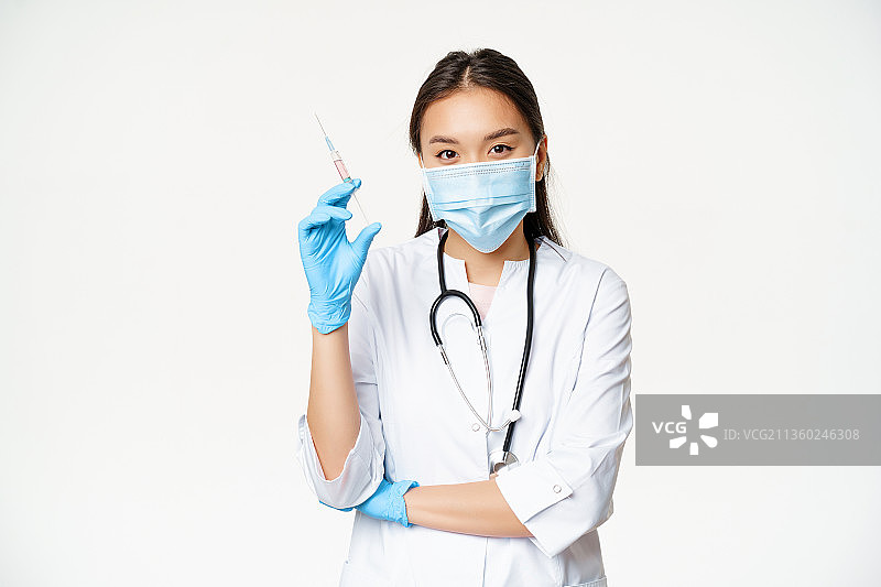 戴着外科口罩站在白色背景下的女医生的肖像图片素材