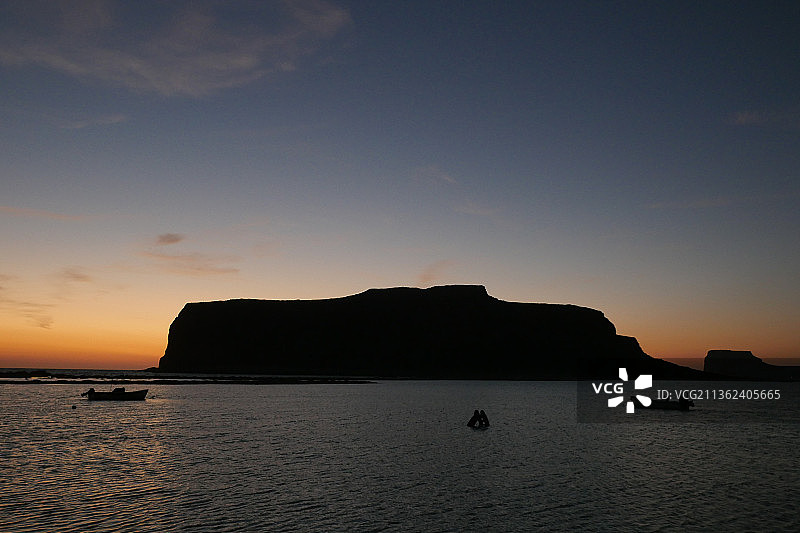希腊克里特岛巴洛斯的日落，日落时海上岩石对天空的剪影图片素材