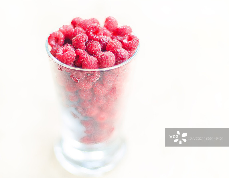 一杯新鲜的树莓，树莓在白色背景玻璃的特写图片素材