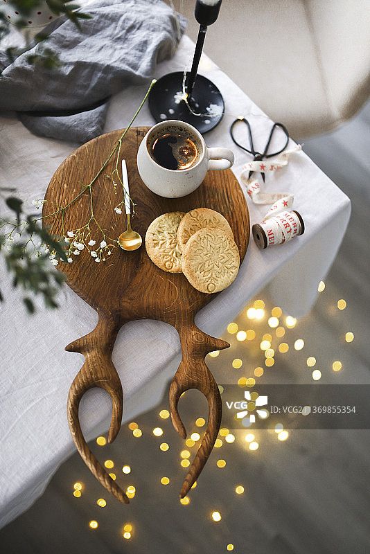 圣诞饼干和一杯咖啡放在鹿角形状的木板上图片素材