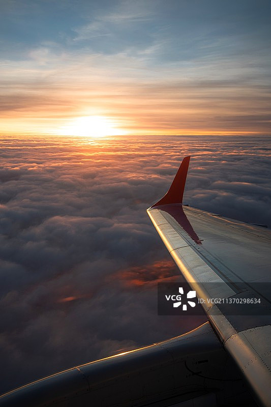维也纳的到来，裁剪图像的飞机机翼飞行在天空中日落图片素材