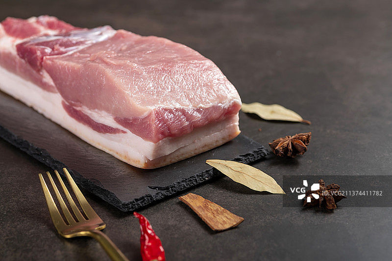 一块新鲜猪肉与香料调料特写黑色背景图片素材